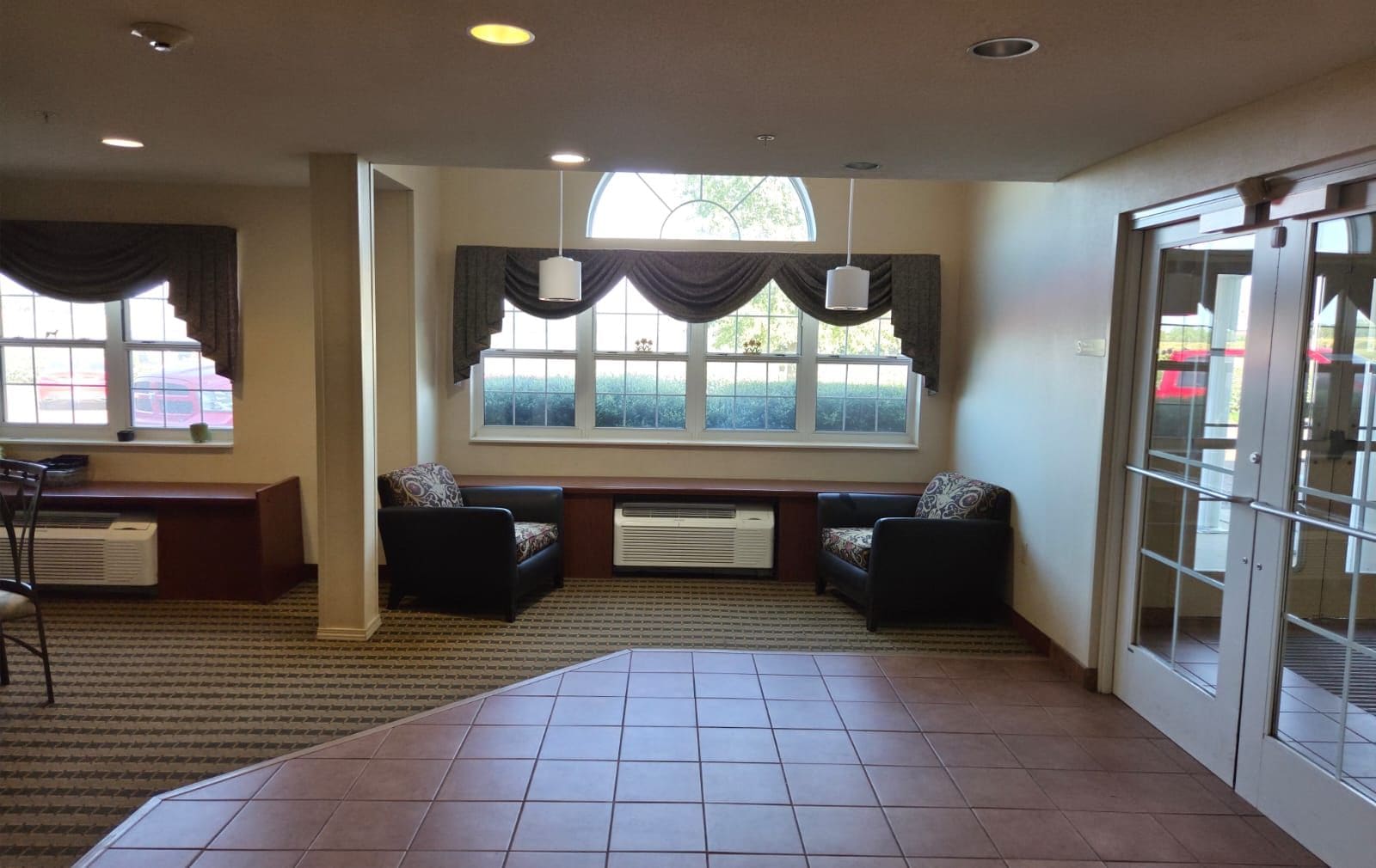 Un hall de hotel con zona de estar, ventanas amplias y suelo de baldosas.
