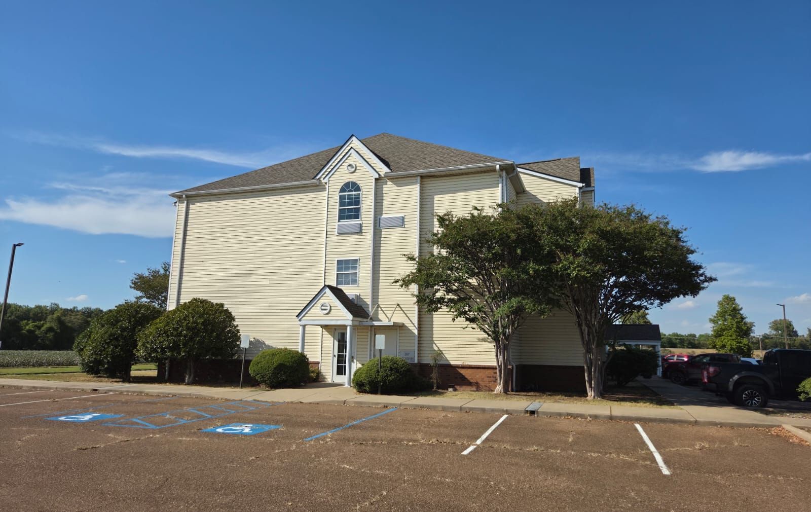 A two-story building with a garage, a covered entrance, and a parking lot with marked spaces.