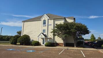 A two-story building with a garage, a covered entrance, and a parking lot with marked spaces.
