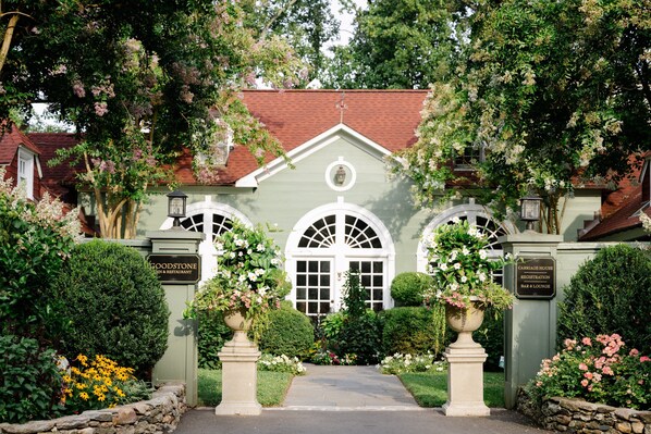 A traditional building with a green facade, white arched windows, and a red roof. There are signs for 'Goodstone Inn & Restaurant' and 'Carriage House Bar & Lounge'.