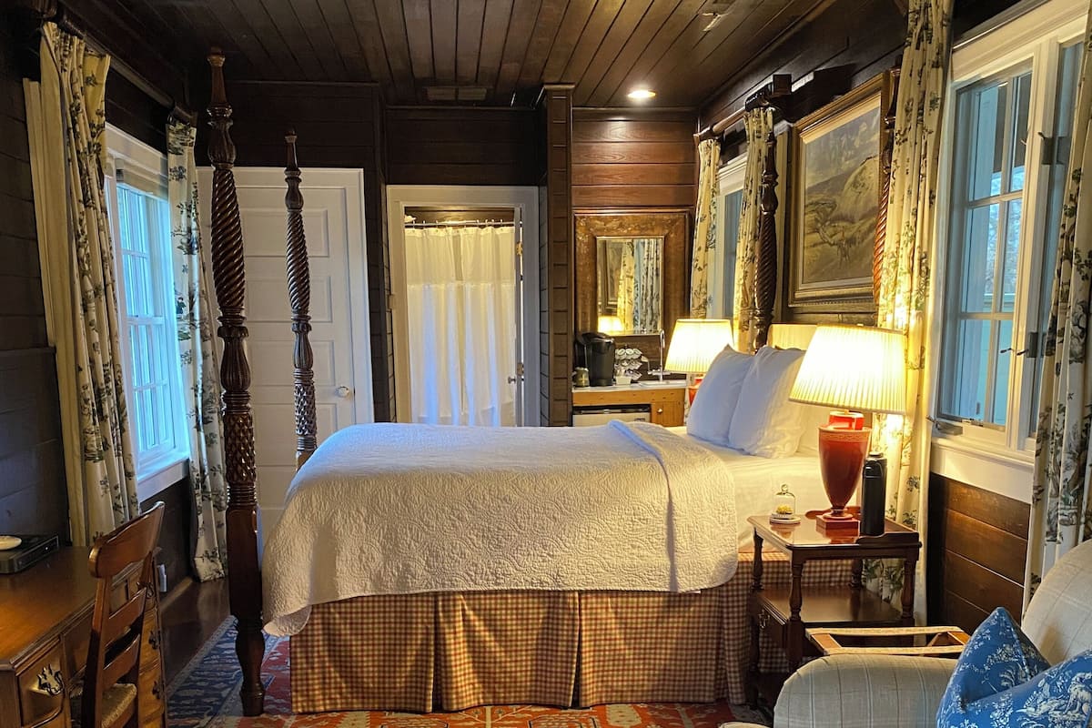 A traditional room with a large bed, a sofa, a wooden table, and a patterned rug.