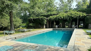 A rectangular swimming pool with a stone deck, surrounded by green lawns and trees. - Goodstone Inn & Restaurant (Middleburg)