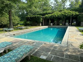 Una piscina al aire libre de temporada, sillones reclinables de piscina