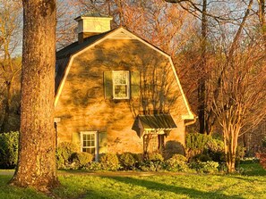 A stone farmhouse with a gabled roof, two windows, and a small porch.