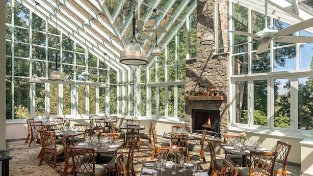 A dining area with tables set for six, large windows, and a stone fireplace. - Goodstone Inn & Restaurant (Middleburg)