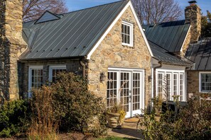 A stone house with a metal roof, white-framed windows, and a stone chimney.