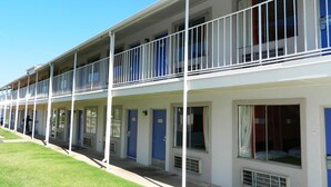 Un motel comprenant plusieurs chambres, chacune étant dotée d’une porte et d’une fenêtre.