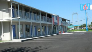 Un motel composé d’un bâtiment à deux étages, d’un parking et d’une enseigne.