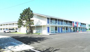 Un motel avec un bâtiment à deux étages, plusieurs chambres et un parking.