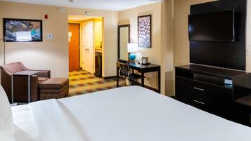Habitación de hotel con cama, escritorio y silla, televisor y puerta que da a otra habitación.