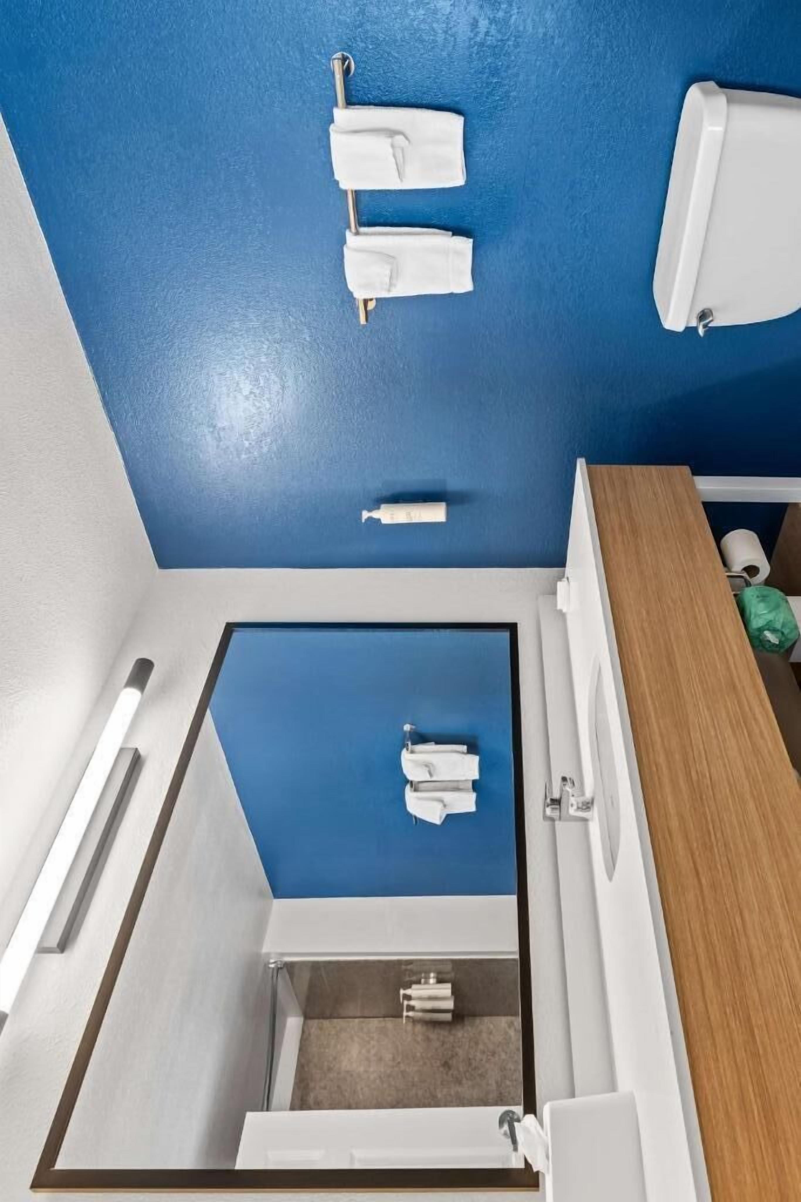 A bathroom with a blue ceiling, white fixtures, and a wooden vanity.