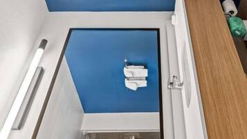 A bathroom with a blue ceiling, white fixtures, and a wooden vanity.