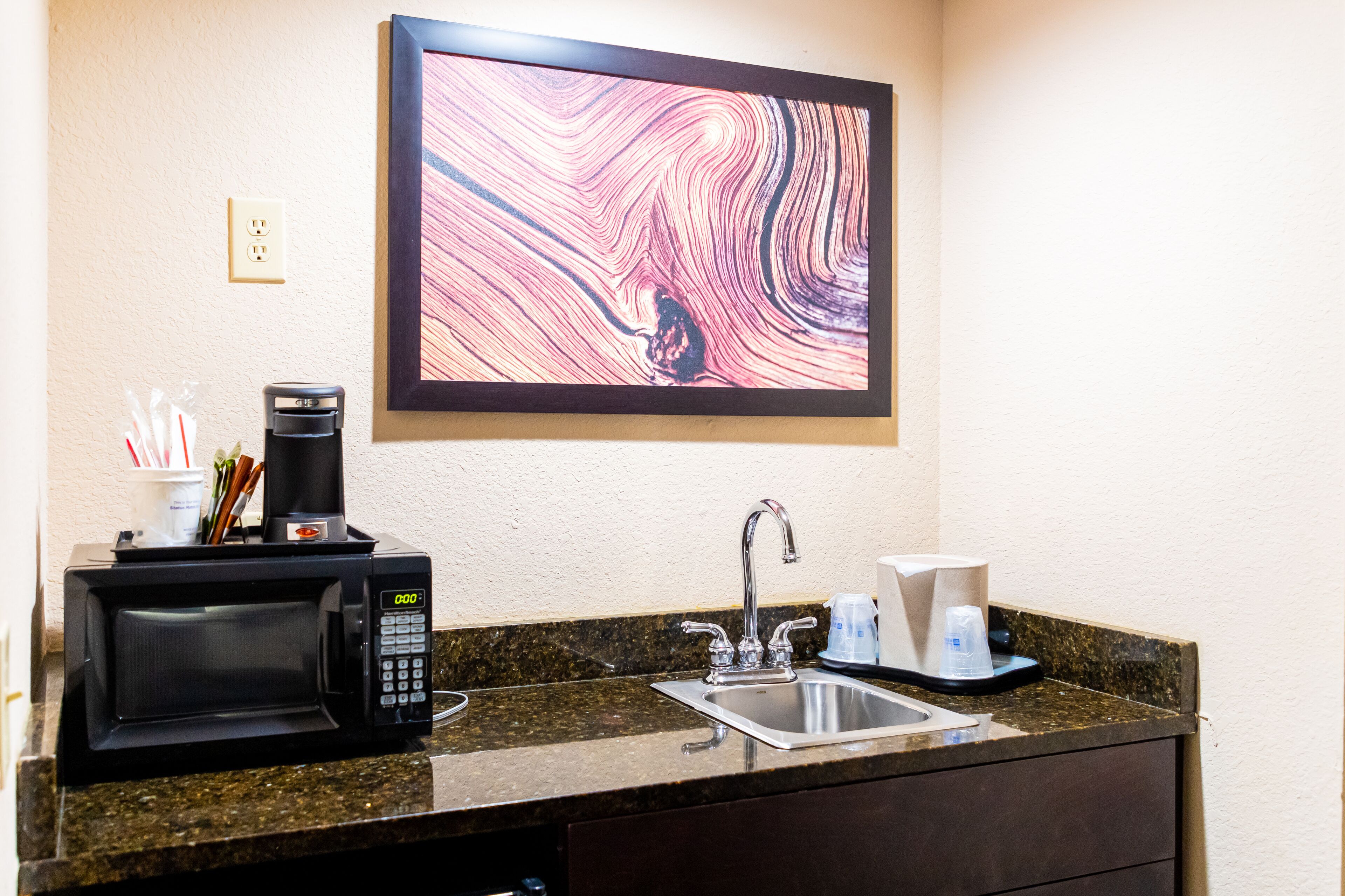 A kitchen with a microwave, coffee maker, and sink.