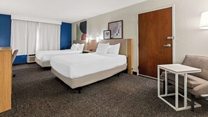 A hotel room with two beds, a desk, a chair, and a small table. - Spark by Hilton Port Wentworth Savannah (Port Wentworth)