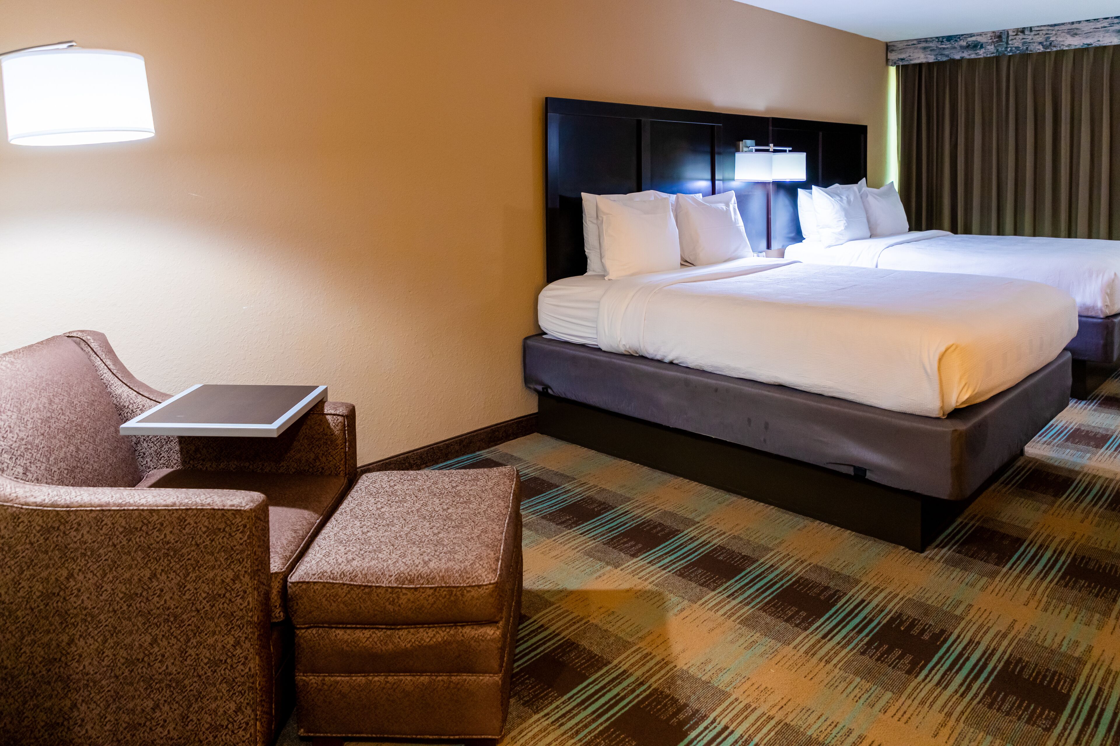 Une chambre d’hôtel avec deux lits, un bureau et une chaise.
