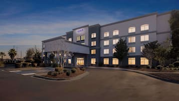 Een modern hotel met een 'spark'-bord, een parkeerplaats en aangelegde groene zones.