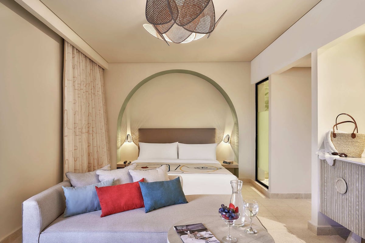 Een moderne hotelkamer met een groot bed, een slaapbank en een eethoek.