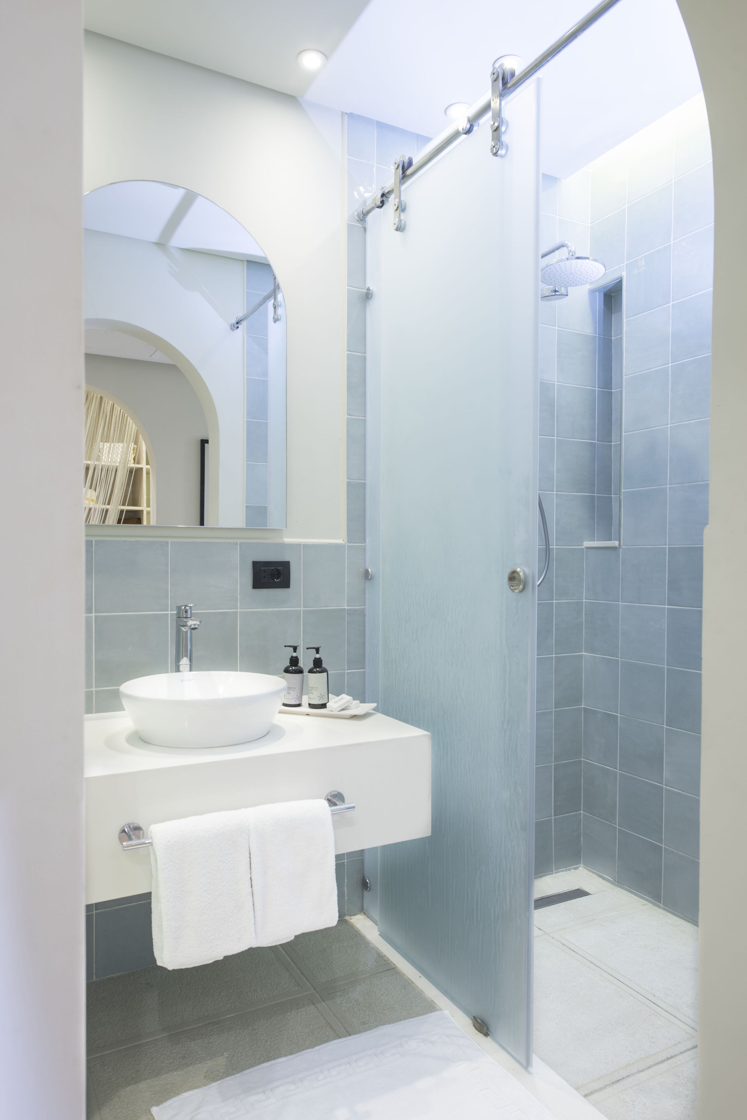 A modern bathroom with a glass-enclosed shower, a white sink, and a mirror above the vanity.