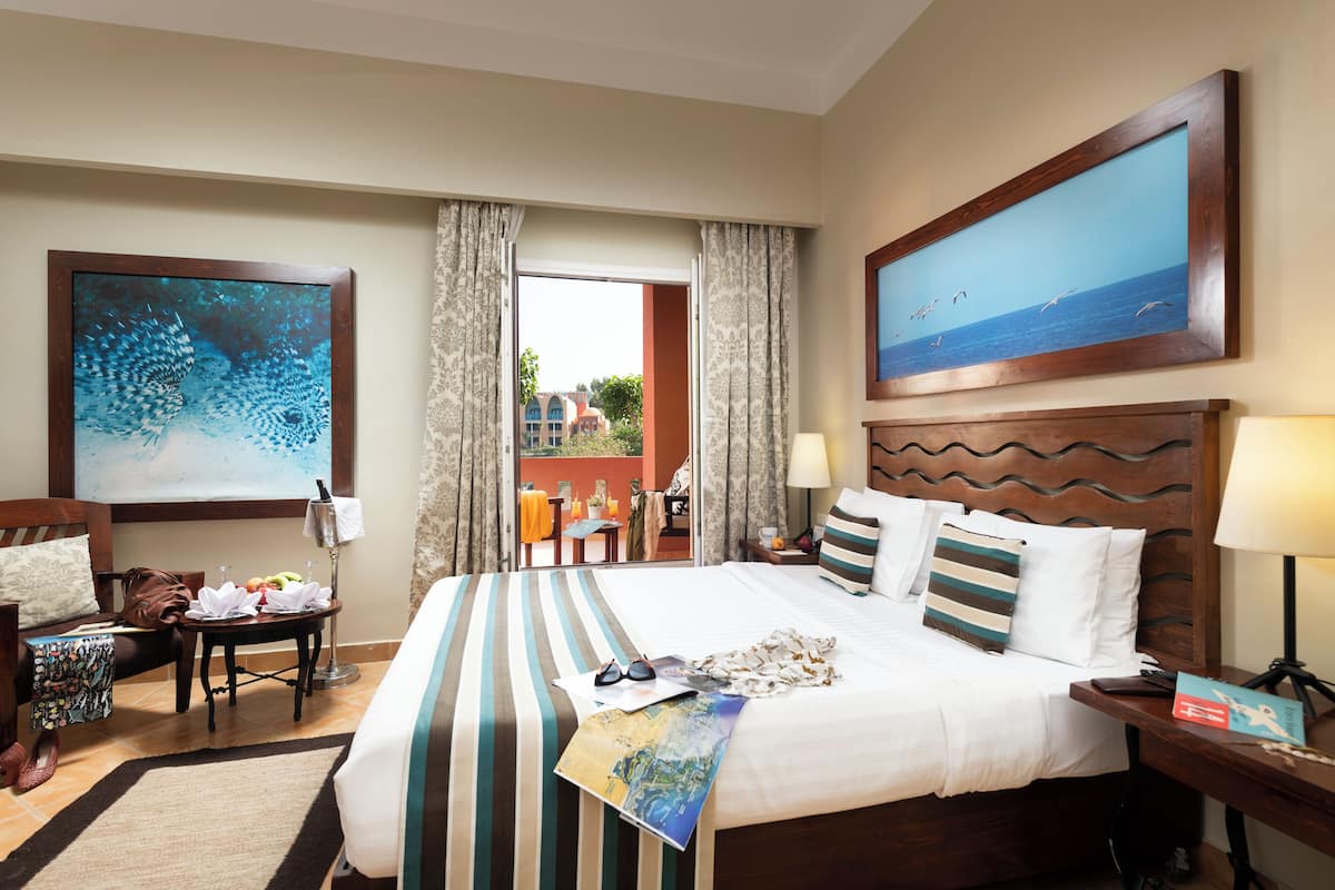 Een hotelkamer met een groot bed, uitzicht en een schilderij aan de muur.