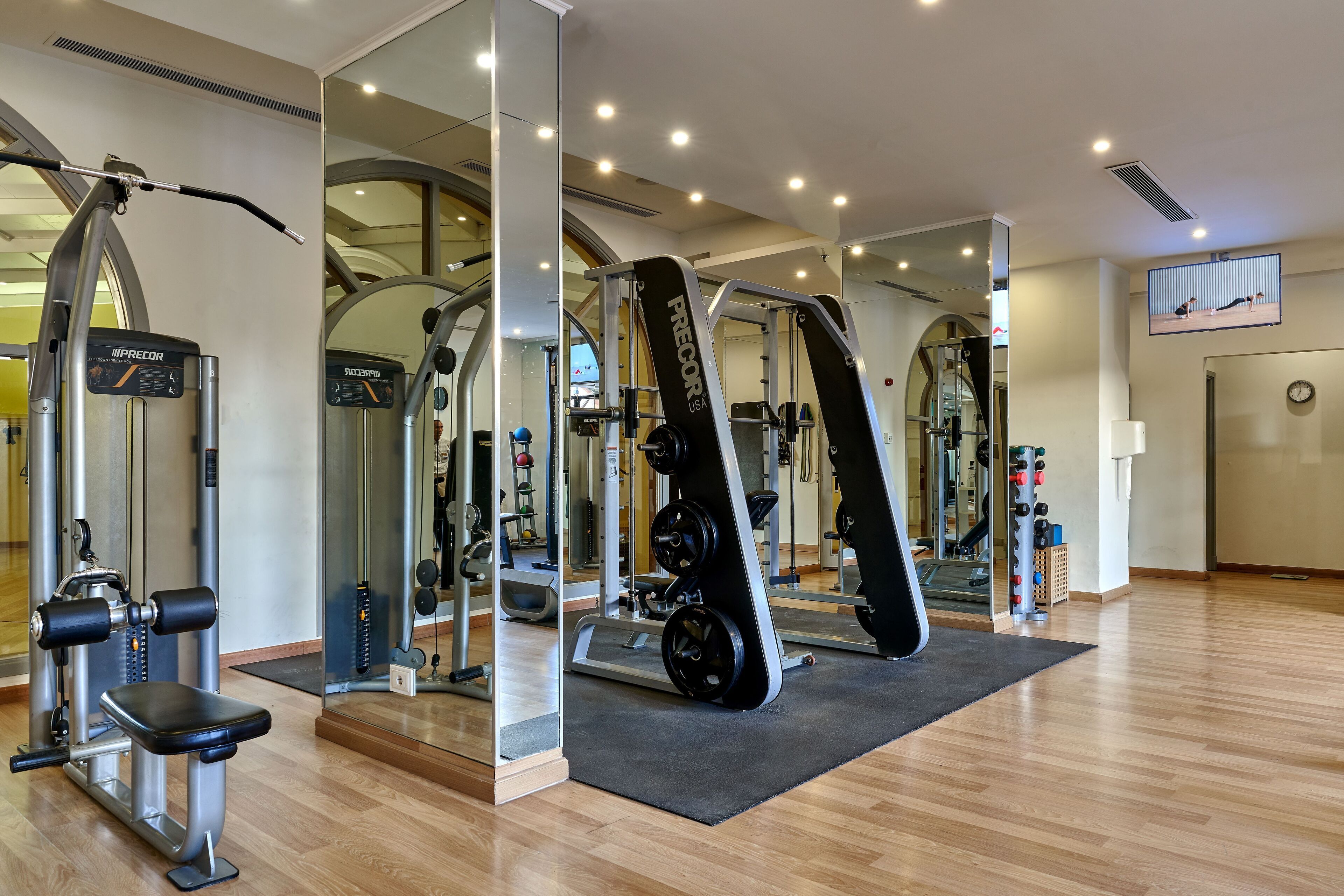 A gym with various exercise equipment, including a bench press, a squat rack, and a cable machine.