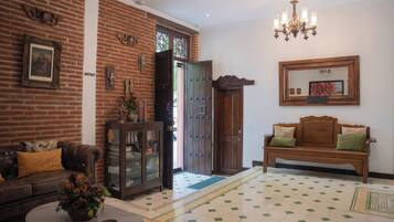 A living room with a brick wall, a wooden bench, a sofa, a cabinet, and a chandelier.