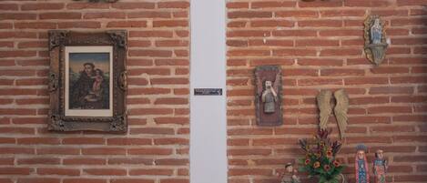 A brick wall with a framed picture, a small plaque, and decorative items including a vase with flowers and figurines.
