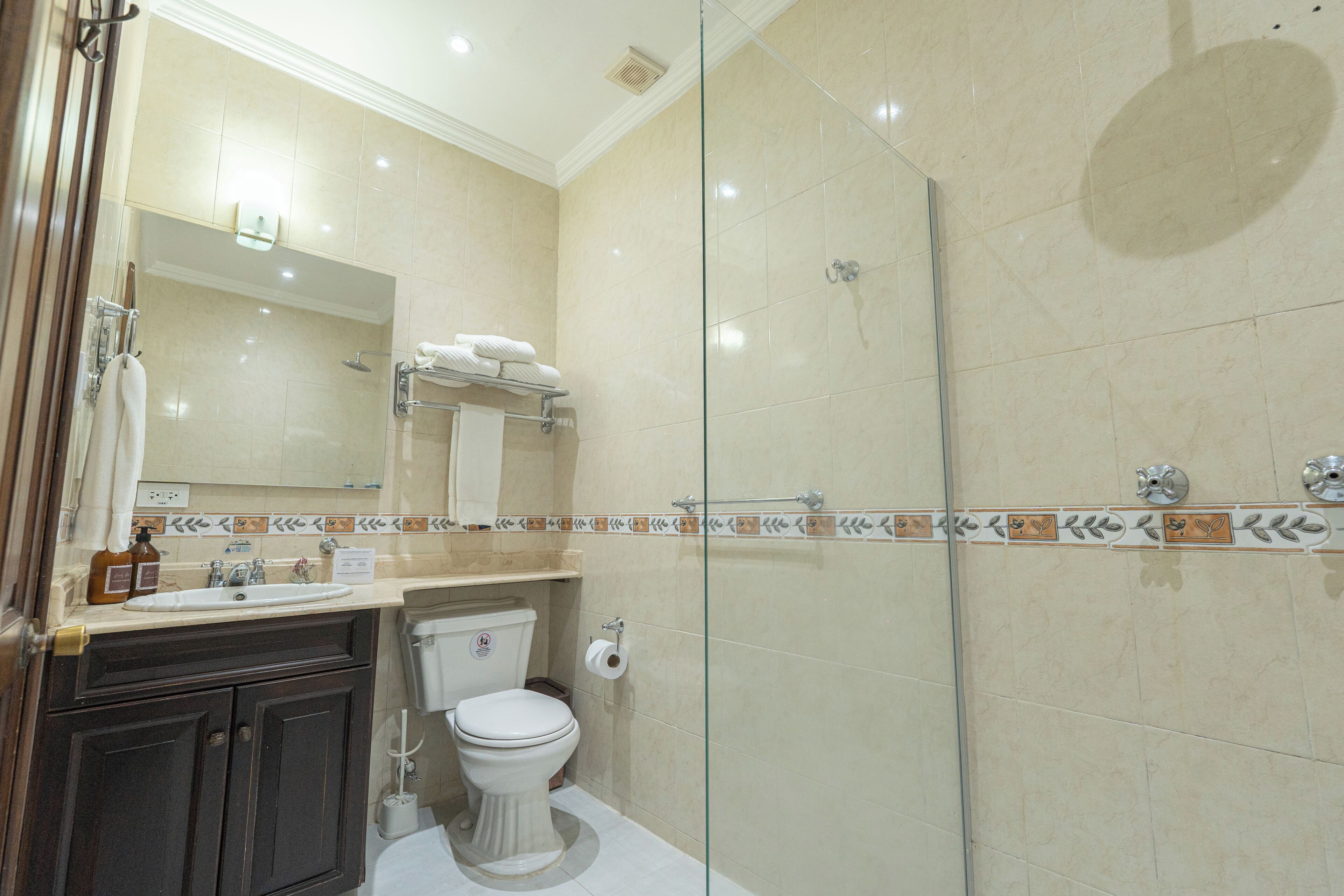 Ein Badezimmer mit Duschkabine aus Glas, Waschbecken mit Spiegel und Toilette.