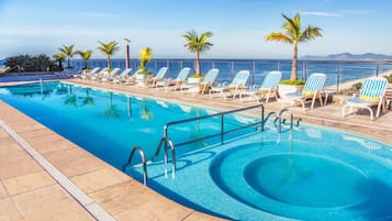 Una piscina al aire libre, sillones reclinables de piscina