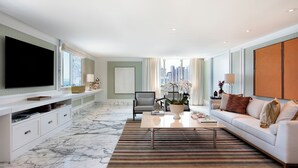 A modern living room with a large flat-screen TV, a sofa, a coffee table, and a potted plant.