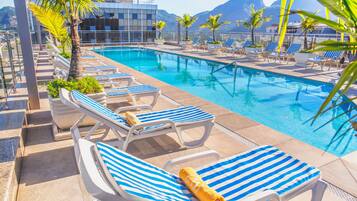 Una piscina al aire libre, sillones reclinables de piscina