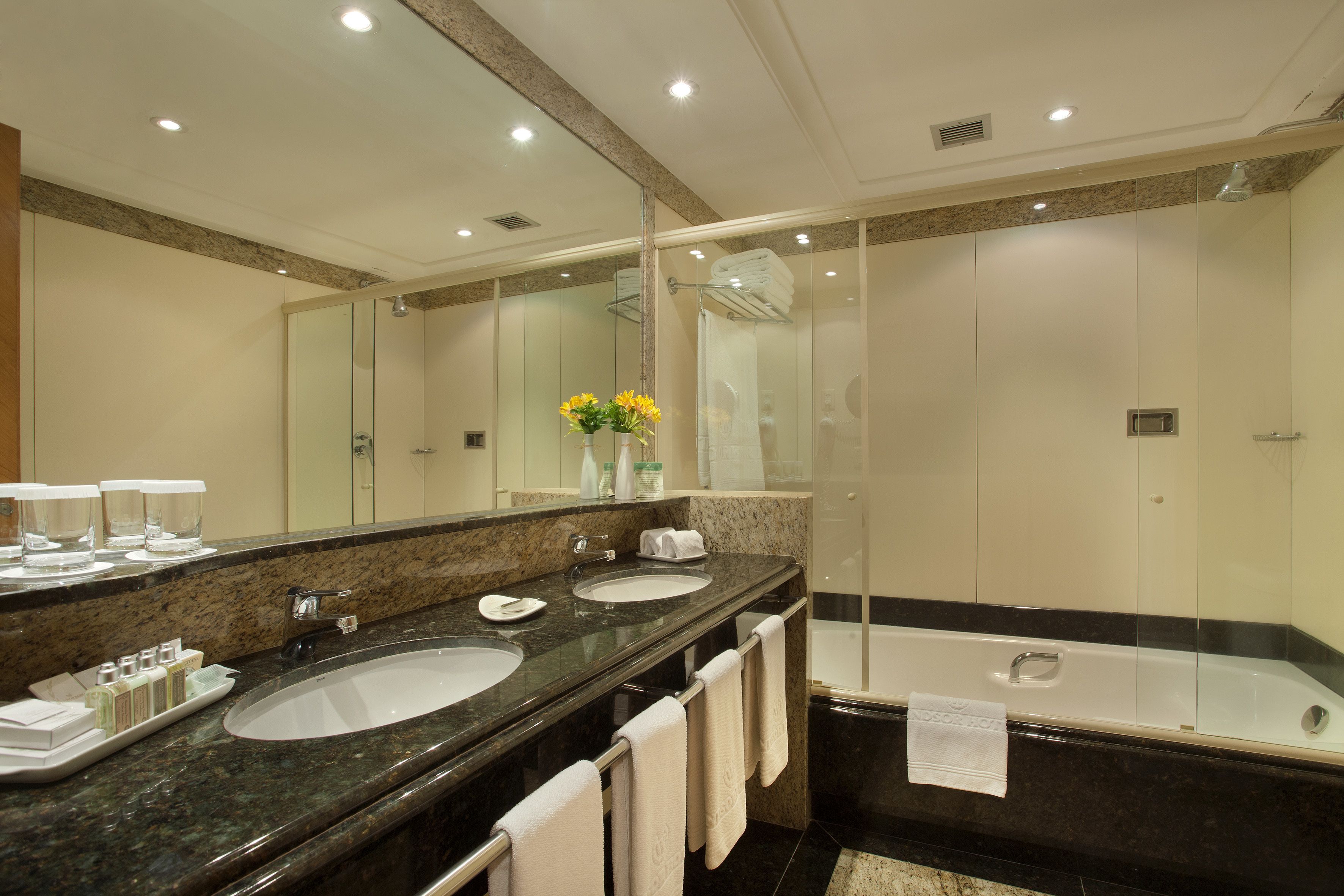 Uma casa de banho moderna com duas pias, um espelho grande e uma área de duche separada.