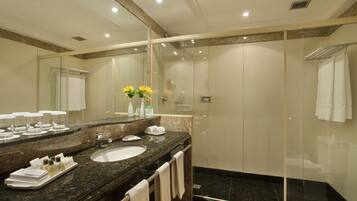 A modern bathroom with a glass-enclosed shower, a large mirror, and a granite countertop.