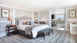 A bedroom with a large bed, bedside tables, a bench, and a desk with a chair.