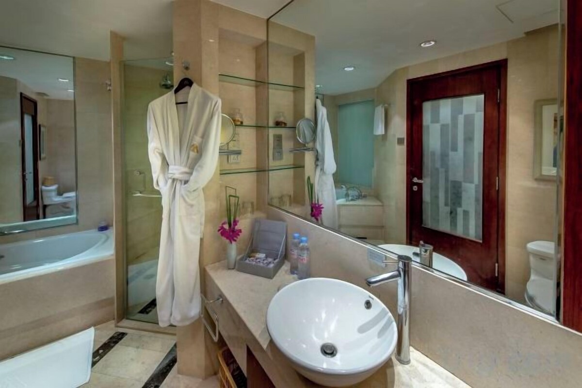 Une salle de bain moderne avec un grand miroir, une baignoire et un meuble-lavabo.