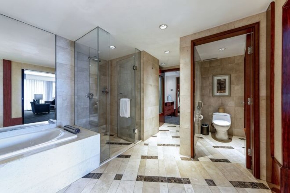 Un baño moderno con ducha envuelta en vidrio, una bañera y un inodoro.