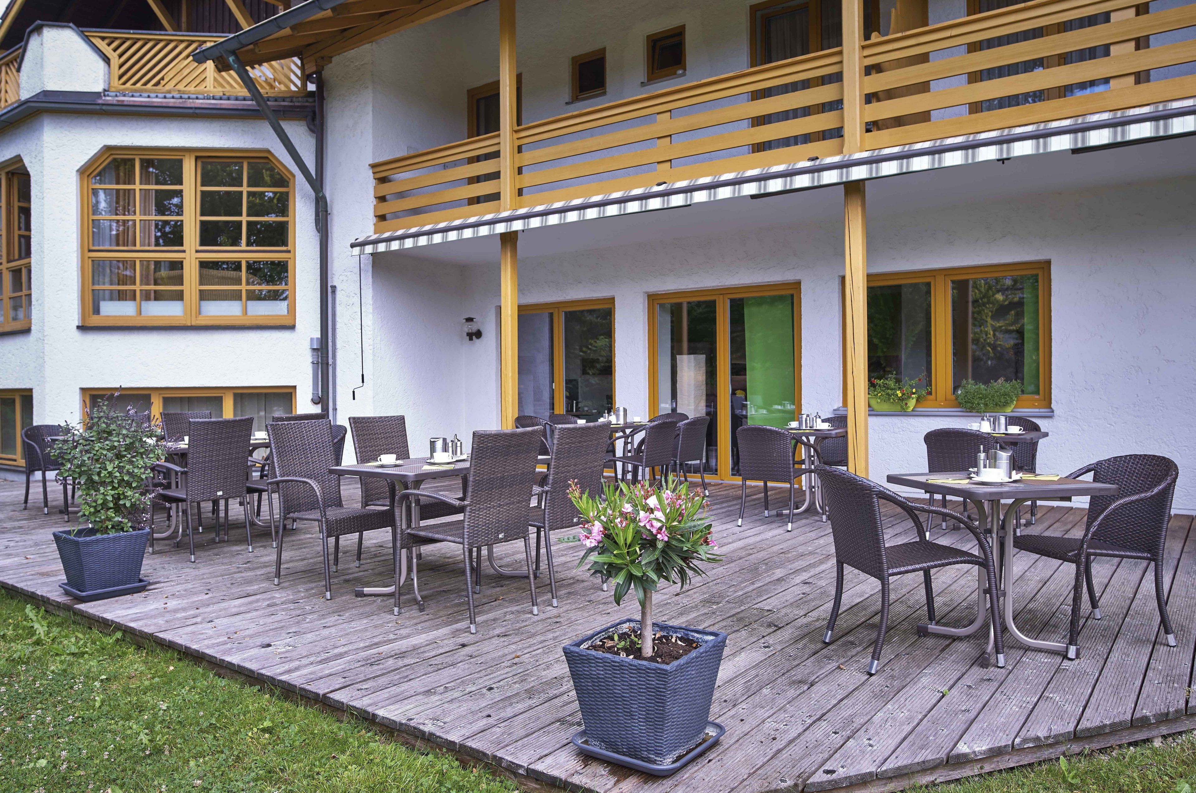Una terraza de madera con mobiliario exterior y una planta en maceta.