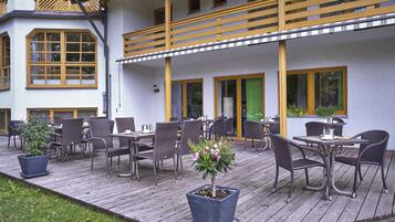 Una terraza de madera con mobiliario exterior y una planta en maceta.
