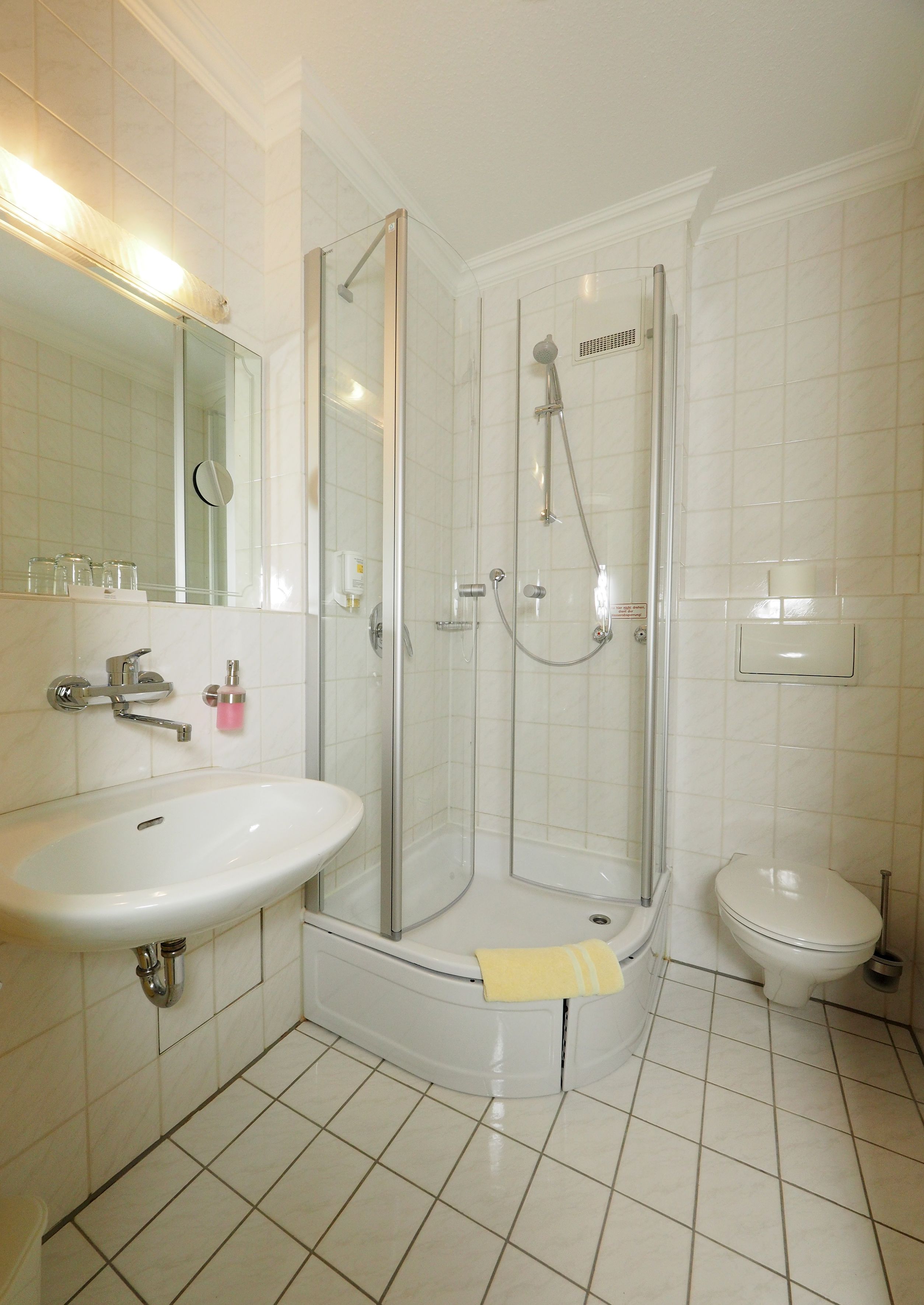 Une salle de bain avec une douche à parois de verre, un lavabo blanc et des toilettes.