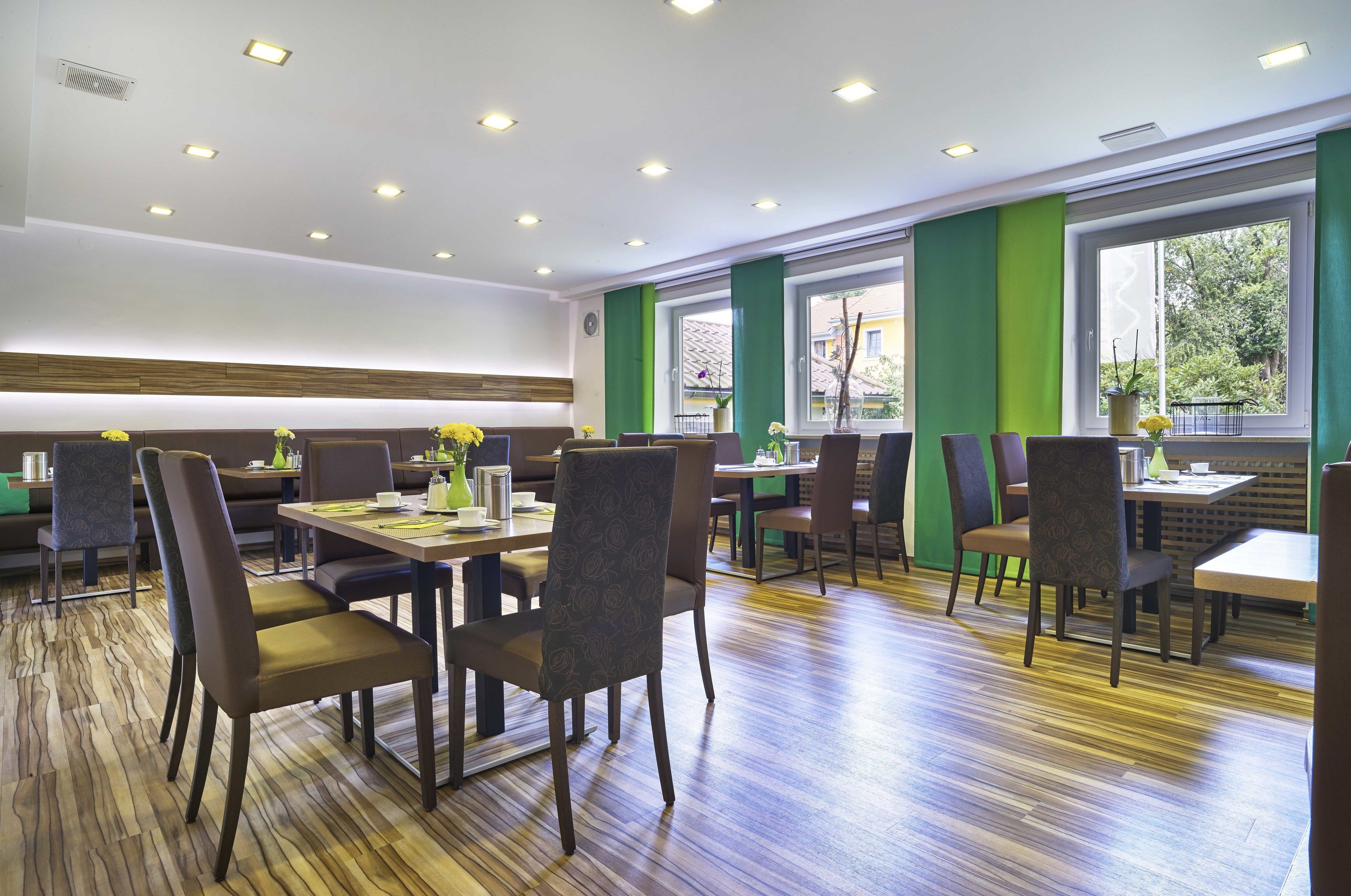 Un restaurante con suelo de madera, paredes verdes de acento y varias zonas de estar, incluyendo cabinas y mesas.