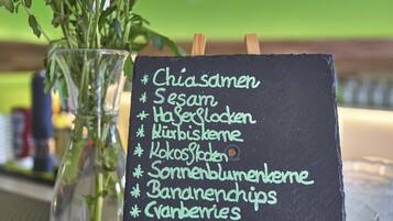 Una pizarra muestra un menú con diversos platos como Chiasamen, Sesam y Hasegelocken.