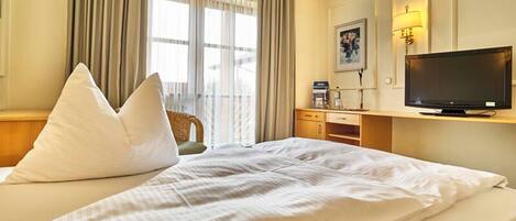 A hotel room with a bed, a television, a desk, and a chair.