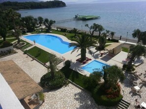 A resort with a large swimming pool, palm trees, and a view of the sea. - Elea Beach (Corfu)