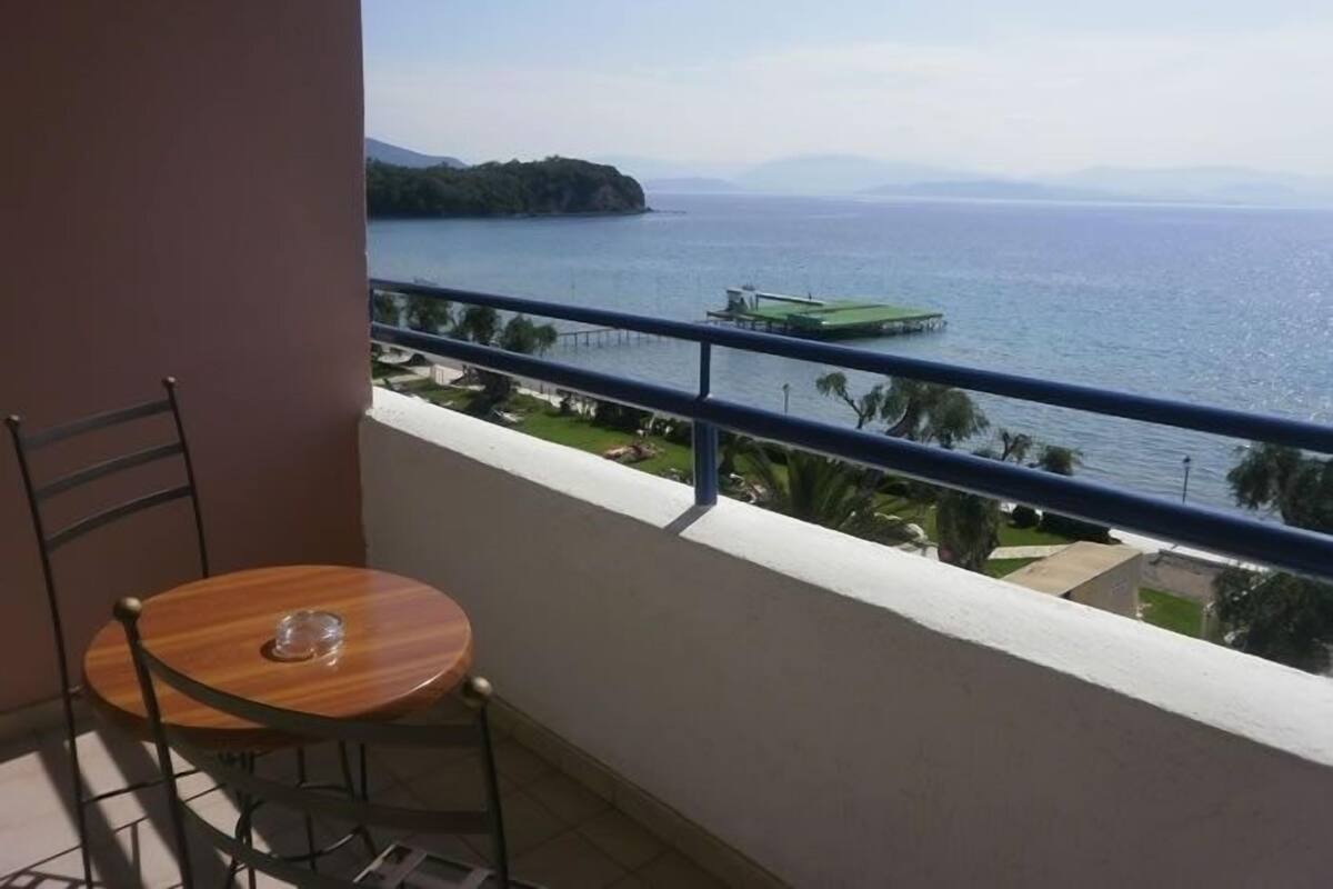 A balcony with a view of the sea, a table, and a chair.