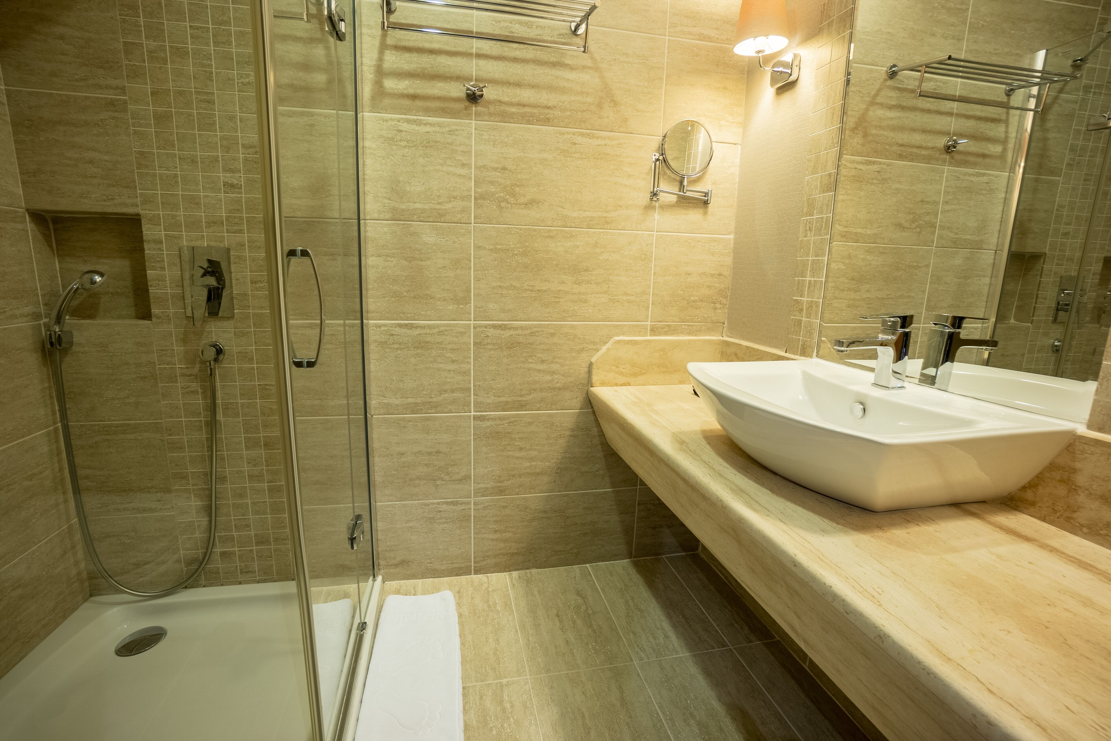 A modern bathroom with a glass-enclosed shower, a large sink, and a mirror.
