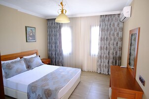 Una habitación de hotel con cama, mesitas de noche, un escritorio y un espejo.