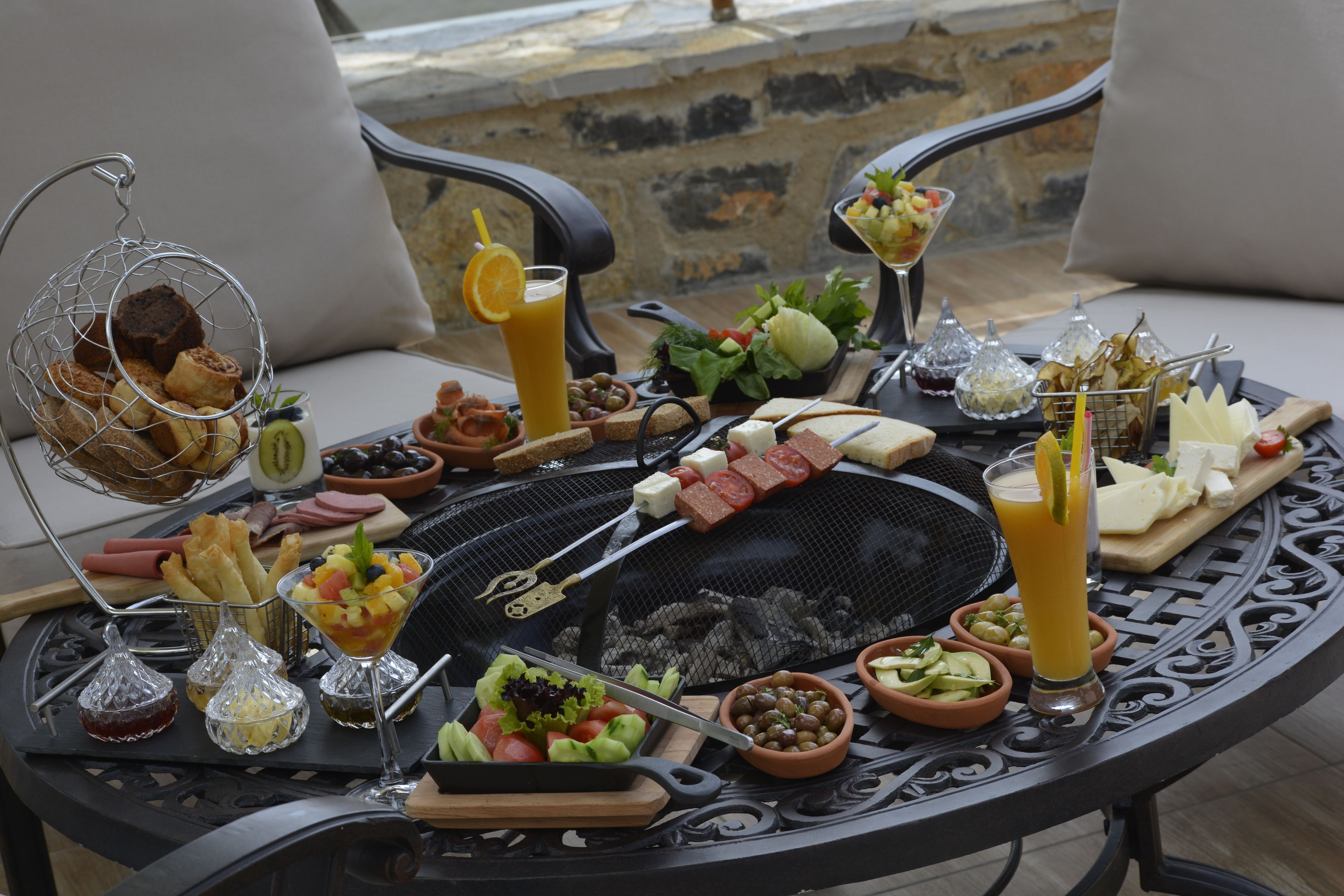A table set with a variety of foods including bread, cheese, and vegetables, along with drinks and condiments.