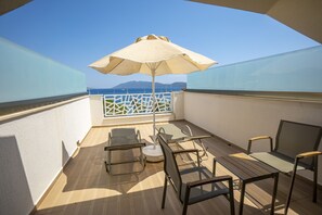 Un balcon avec une table, des chaises et un parasol.