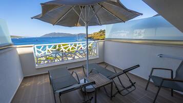 Enjoy the ocean view from this balcony with a table and two chairs, shaded by a large umbrella.