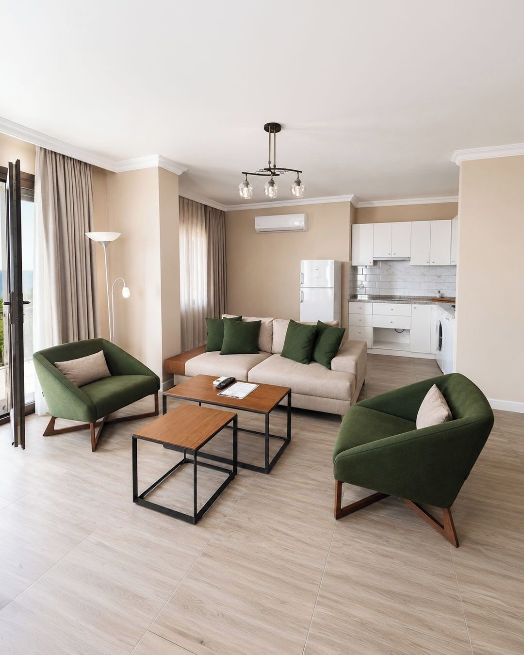 Una sala de estar moderna con un sofá, dos sillones, una mesita de centro y una cocina al fondo.
