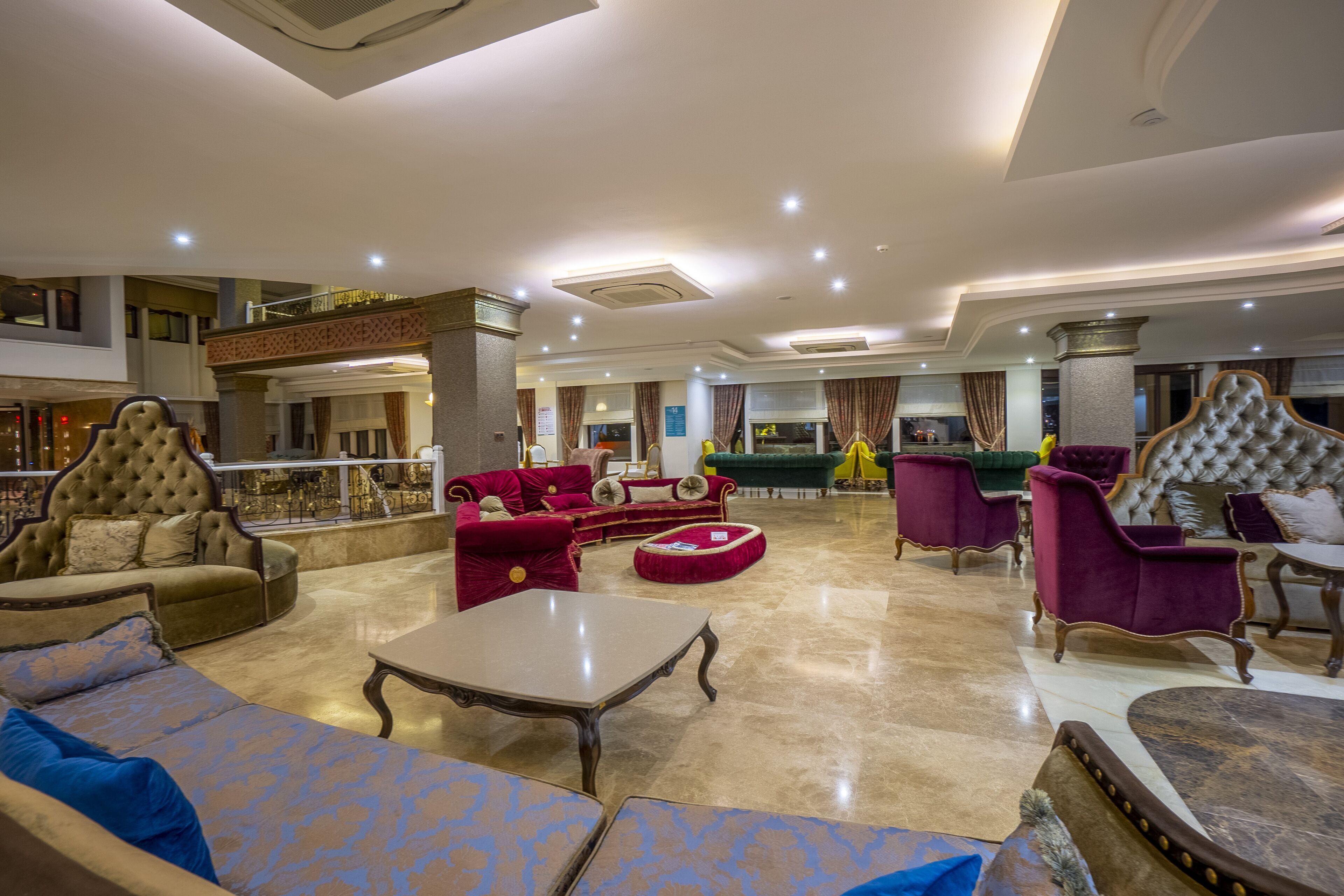A spacious lobby with multiple seating areas, including sofas and armchairs, and a central coffee table.